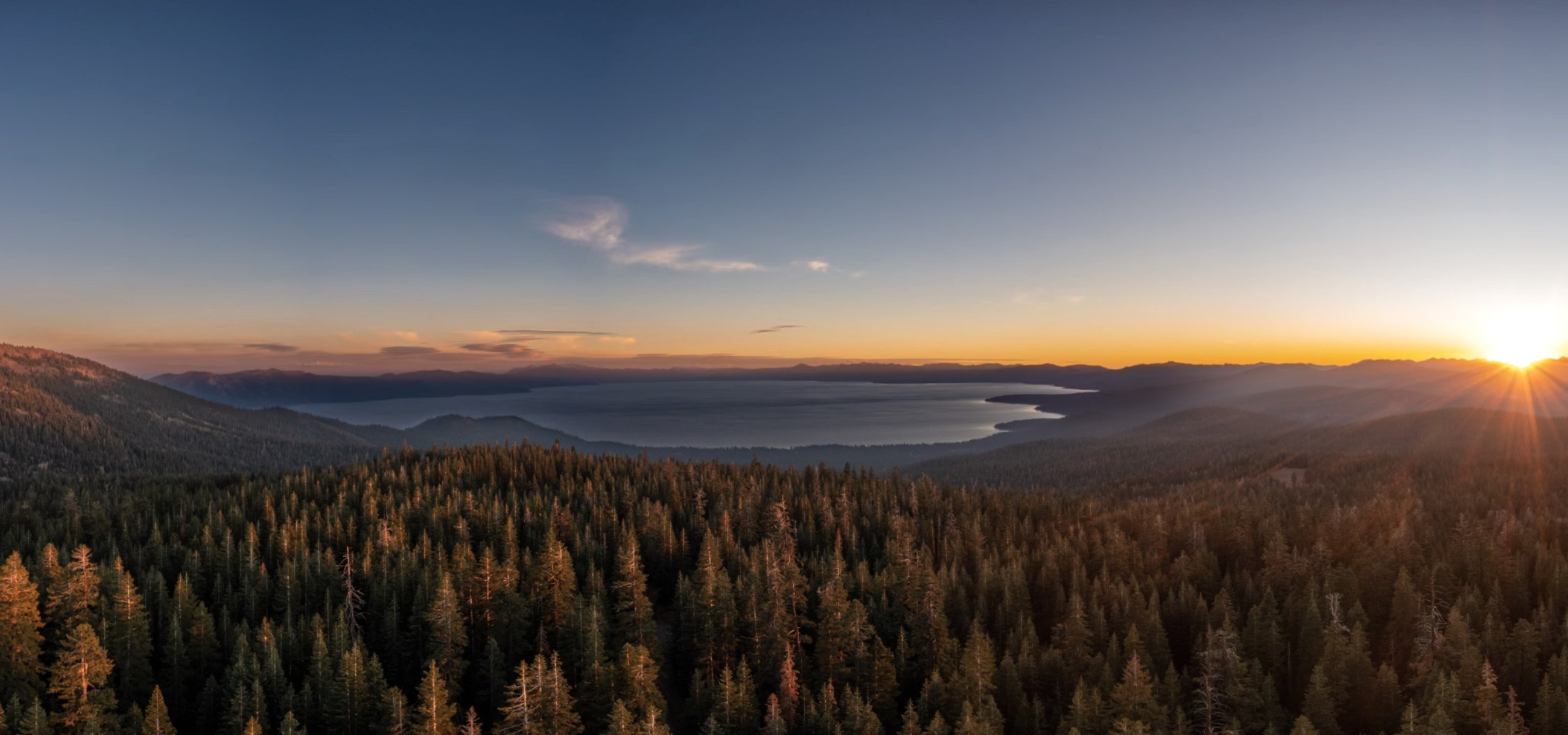 Aerial view of a forest and lake at sunrise