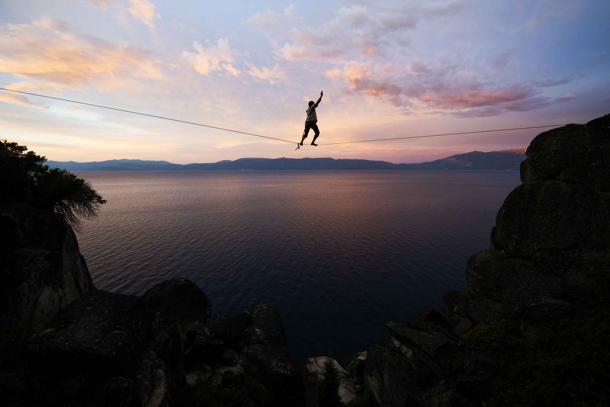 A person slacklining above Lake Tahoe at sunset.