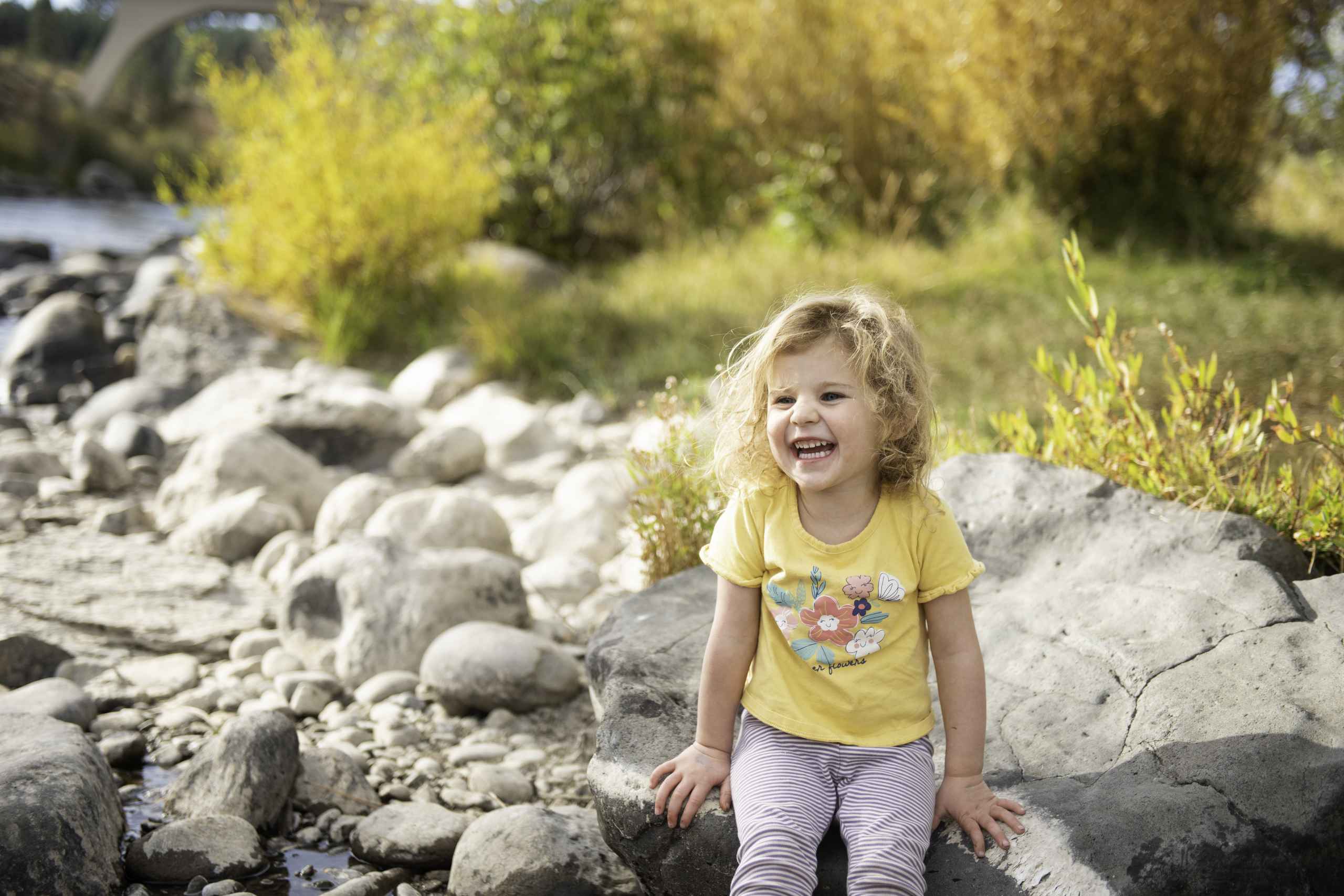 A young girl on a rocky lakeshore.