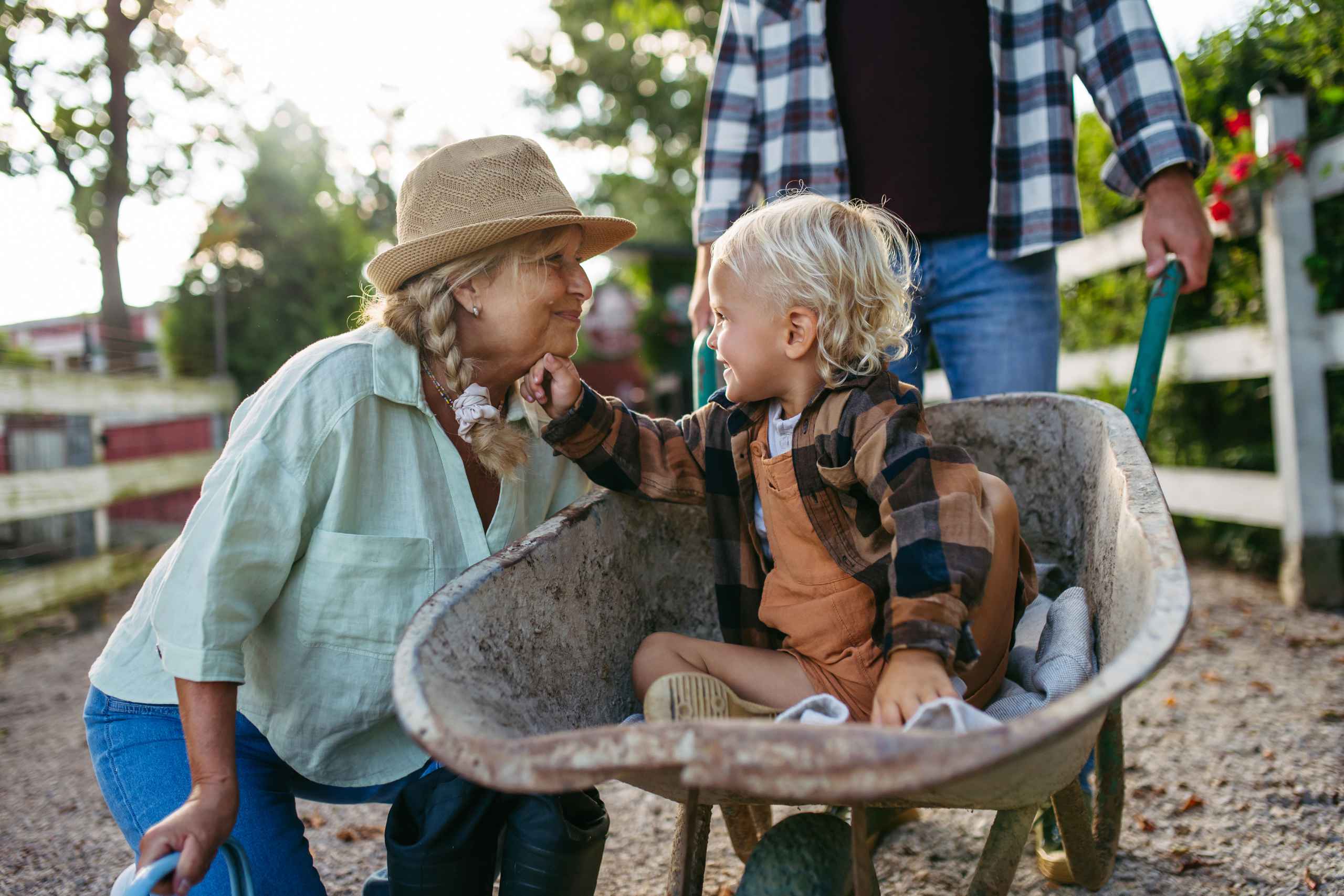 Grandparents giving a grandchild a ride in a wheelbarrow.